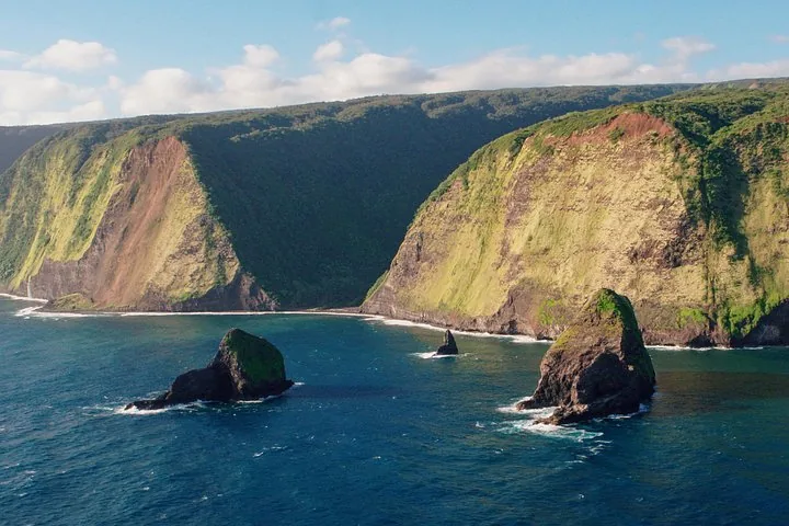 Aerial view of steep green sea cliffs and rock stacks along a rugged coastline