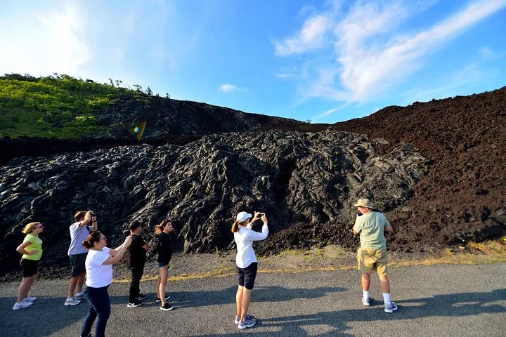 Visitors photographing a ropy black lava flow beside a paved road