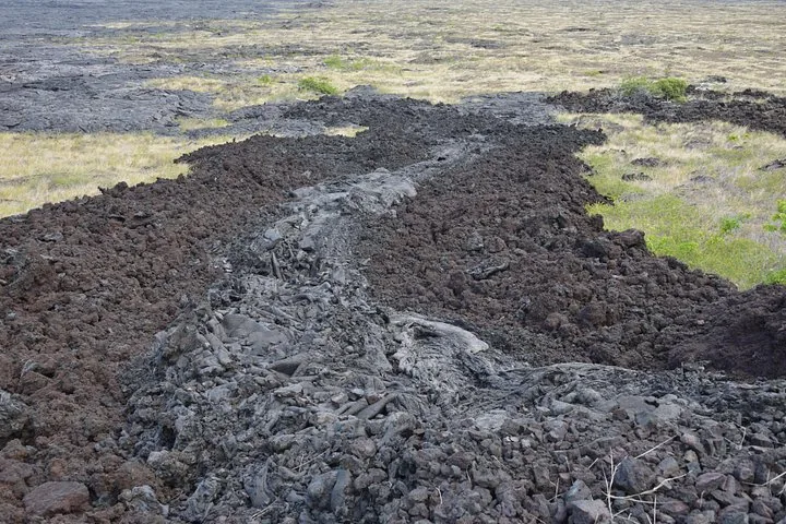 Dark rubbly lava flow cutting across grassland and older gray lava