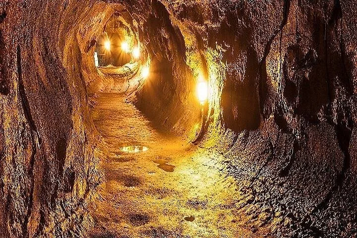 Lights glowing along the damp floor and walls inside a lava tube