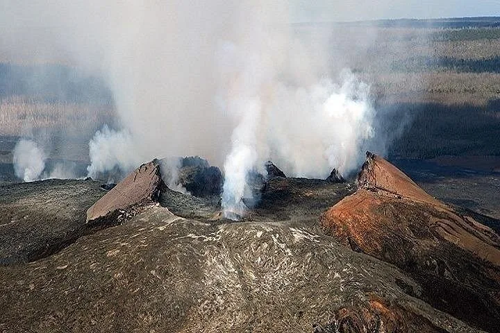 Aerial view of a volcanic cone with gas pouring from its open vents