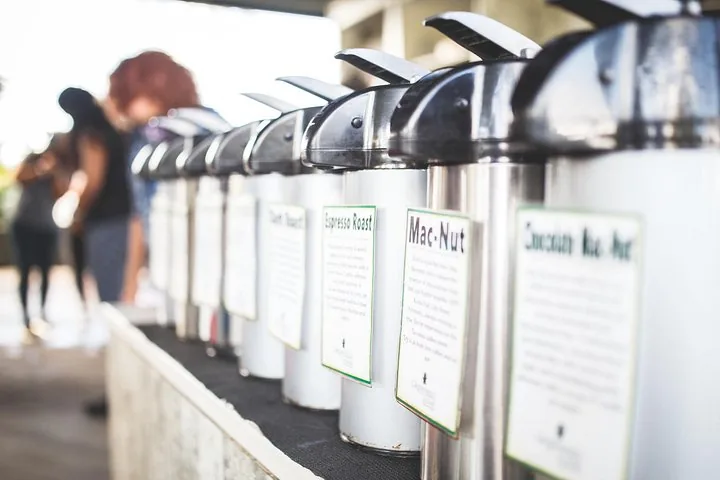 Row of labelled coffee dispensers, including Mac-Nut and Espresso Roast, at a tasting bar