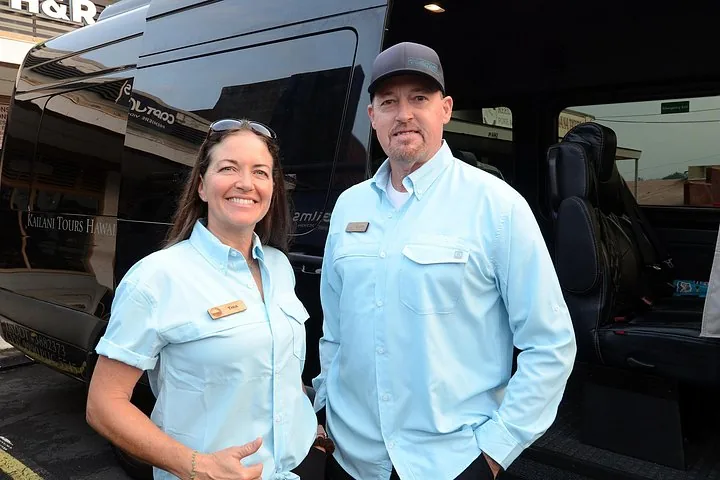 Two Kailani Tours guides in blue shirts beside their black Mercedes Sprinter van